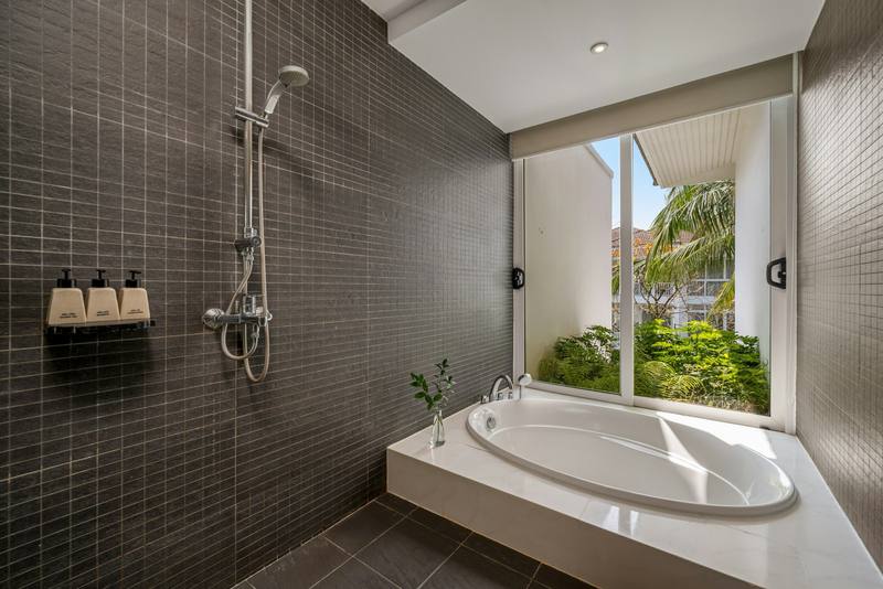 Spa-like bathroom with dark mosaic tiled shower area, rain shower column and soaking tub