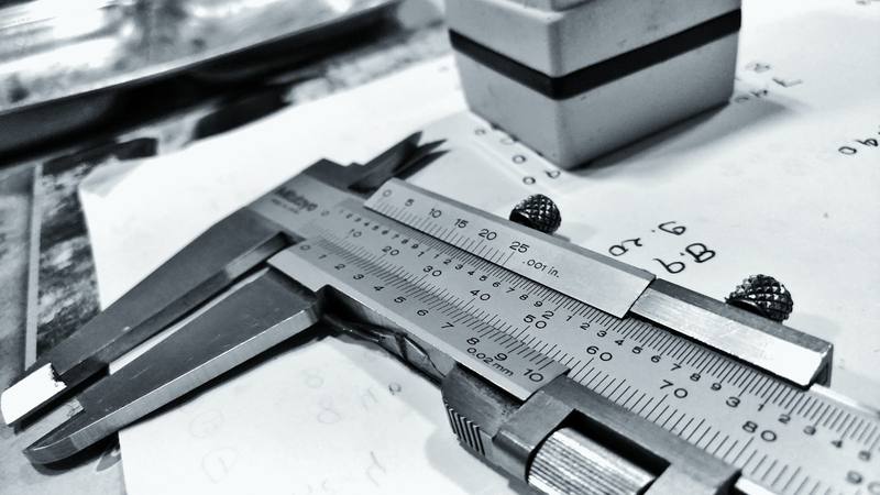 Caliper close-up with millimeter and inch scales, as used to measure glass thickness
