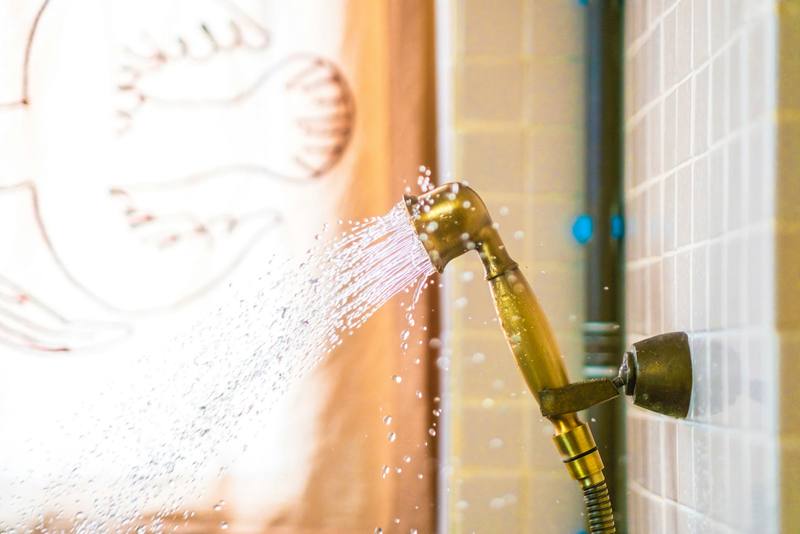 Hand-held shower head spraying water inside a tiled shower