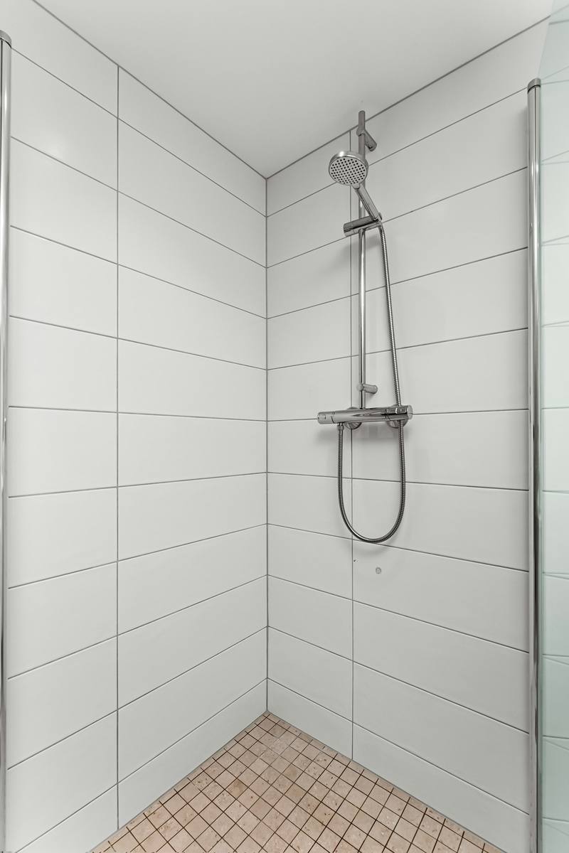 Walk-in shower interior with white tiled walls and glass panels on both sides